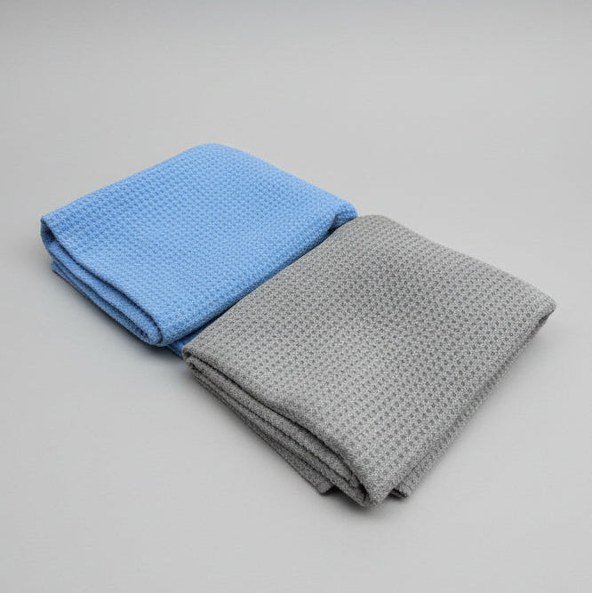 Two folded towels, one blue and one gray, on a white background